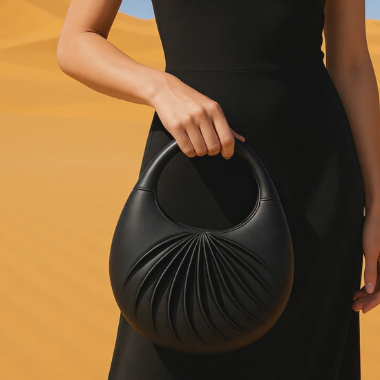 Video of Sirah, an elegant black leather moon bag, handcrafted in France, on a mannequin in the dune