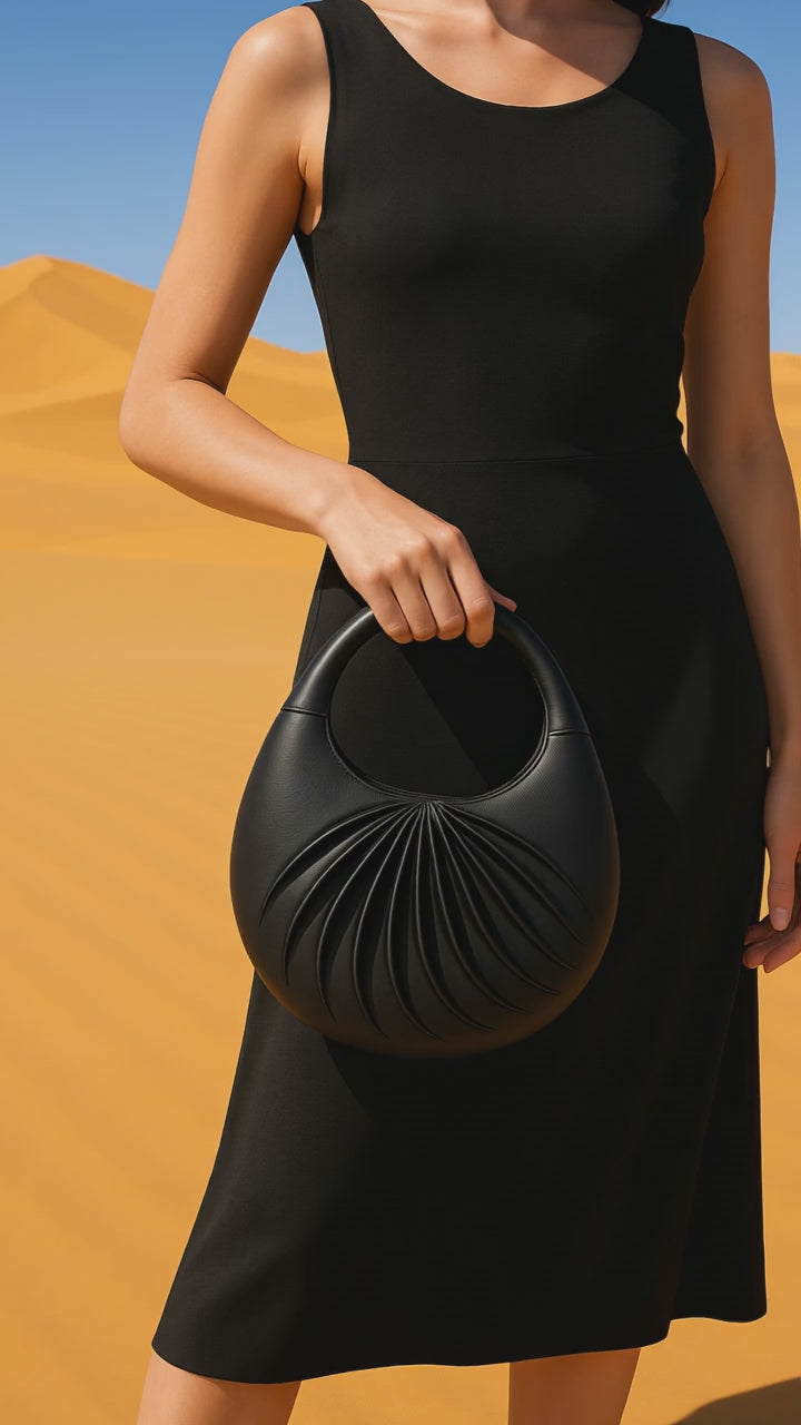 Video of Sirah, an elegant black leather moon bag, handcrafted in France, on a mannequin in the dune